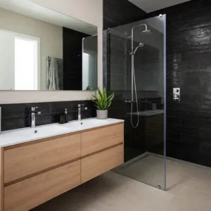 Une salle de bain avec une douche à l'italienne. Un meuble double vasque moderne. Du carrelage foncé sur les murs, et un sol claire.